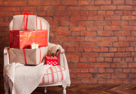 Christmas presents on the armchair on a brick wall background. View with copy spaceの写真素材