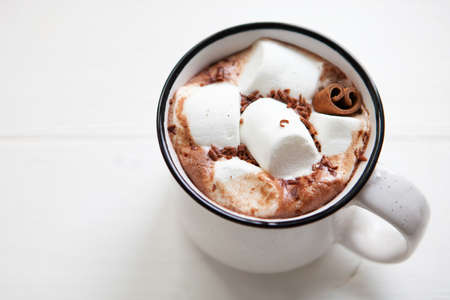 Big cup hot chocolate with marshmallows in a ceramic cup on white wooden surface