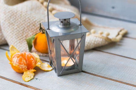Christmas still life with lantern, plaid, mandarin and red beads on grey wooden backgroundの写真素材