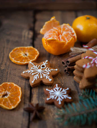 Christmas composition. Xmas cookies, tangerines, cinnamon, festive decoration, fir branches on dark old wooden background. Copy space.の写真素材