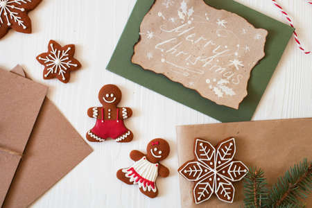 Christmas composition. Xmas cookies, Gingerbread man, ribbon, card, festive decoration, fir branches on white wooden background. Flat lay, top view, with copy space. Close Upの写真素材