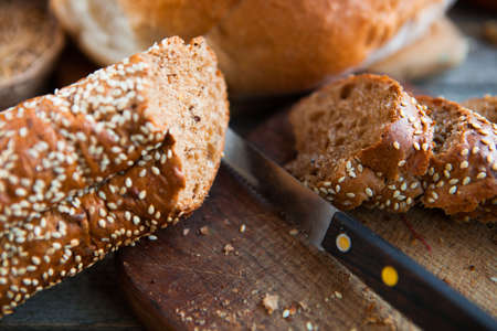Fresh bread slice and cutting knife on old wooden tableの写真素材