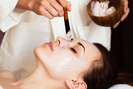 Beautiful woman with facial mask at beauty salon. Spa treatment. 