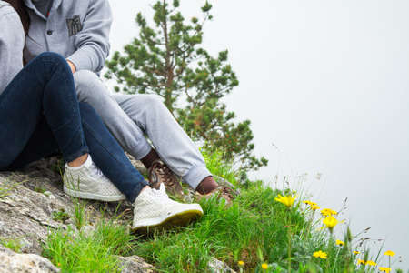 Close up, young couple  in love sitting on a mountain, hugging and looking away, love and feelings conceptの写真素材