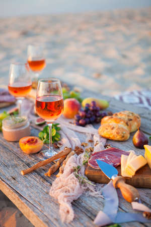 Picnic on the beach at sunset in the style of boho, food and drink conceptionの写真素材