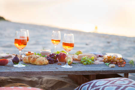 Picnic on the beach at sunset in the style of boho, food and drink conceptionの写真素材