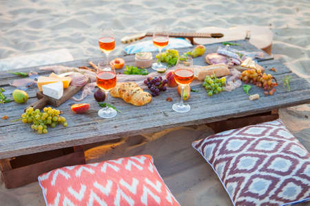 Picnic on the beach at sunset in the style of boho, food and drink conceptionの写真素材
