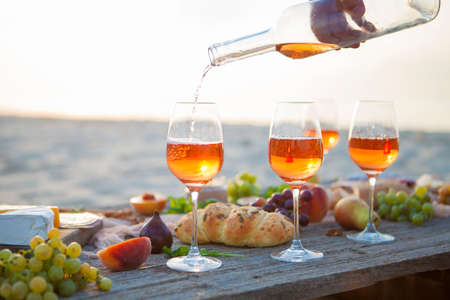 Picnic on the beach at sunset in the style of boho, food and drink conception