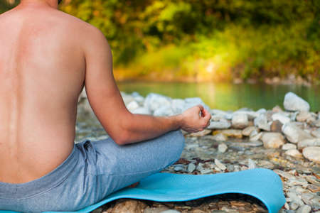 Caucasian man meditating near the mountain river. Yoga practicing outdoors.の写真素材