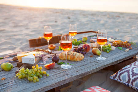 Picnic on the beach at sunset in the style of boho, food and drink conceptionの写真素材