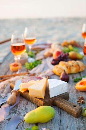 Picnic on the beach at sunset in the style of boho, food and drink conceptionの写真素材