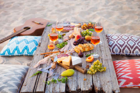 Picnic on the beach at sunset in the style of boho, food and drink conceptionの写真素材