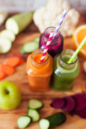 Freshly squeezed vegetable juice in bottles, useful vitamin cocktail, old wooden background, selective focusの写真素材