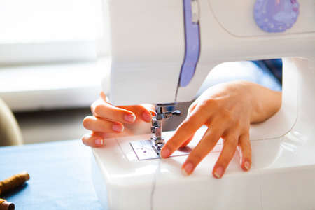 Woman tailor working on sewing machine. Hands. close up. Tailoring. Details. Close up