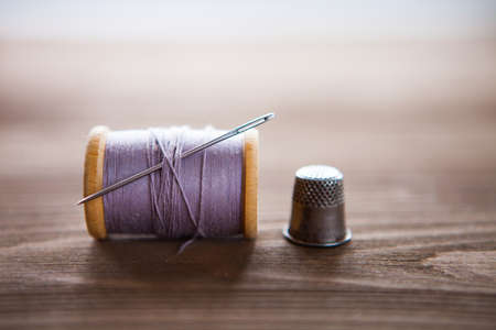 Vintage spool of thread with needle closeup. Tailor's work table, textile or fine cloth making. Horizontalの写真素材