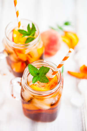 Homemade iced lemonade with ripe  peaches and fresh mint. Fresh peach ice tea in a mason jar. Copy space background.の写真素材