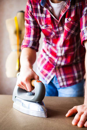 Tailor ironing the fabric. seamstress irons dress in a sewing workshop, close upの写真素材