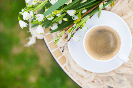 Bouquet White spring bellflowers and coffee cup on table in garden. Spring morning with coffee.の写真素材