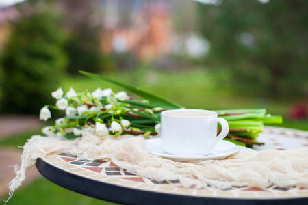 Bouquet White spring bellflowers and coffee cup on table in garden. Spring morning with coffee.の写真素材