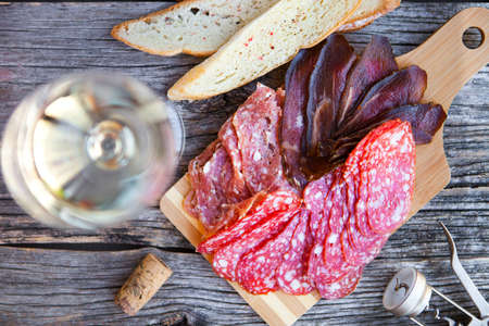 Wine snack set. Glass of white wine, grape, cheese, over rustic wooden background. Top view, copy space, horizontal composition.の写真素材