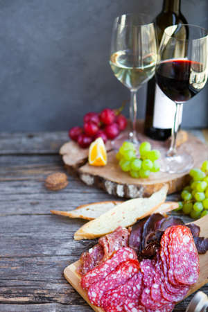 Wine snack set. Glass of red and white wine, grape, cheese, over rustic wooden background. Top view, copy space, horizontal composition.の写真素材