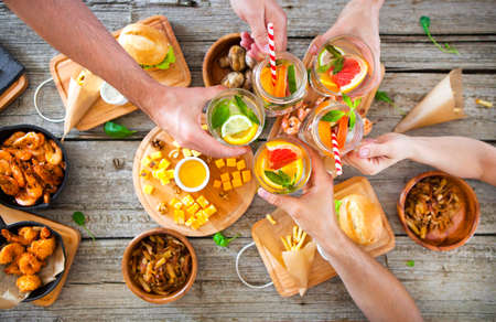 Enjoying dinner with friends toast with lemonade, Top view of group of people having dinner together while sitting at the rustic wooden table. food and drink concept,の写真素材