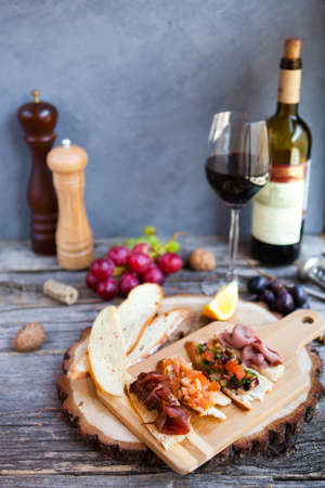 Wine snack set. Glass of red and white wine, grape, cheese, over rustic wooden background. Top view, copy space, horizontal composition.の写真素材