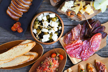 Wine snack set. Glass of red and white wine, grape, cheese, over rustic wooden background. Top view, copy space, horizontal composition.の写真素材