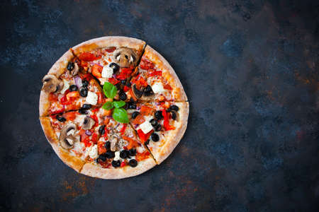 Hot testy pizza with tomatoes, mozzarella, mushrooms, olives, red pepper and basil on black concrete background. Copyspace. Top view. Banner.の写真素材