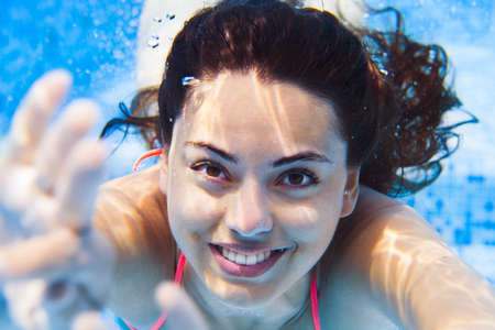 Portrait Young smiling woman swimming undewater in the swimming pool, summer patyの写真素材