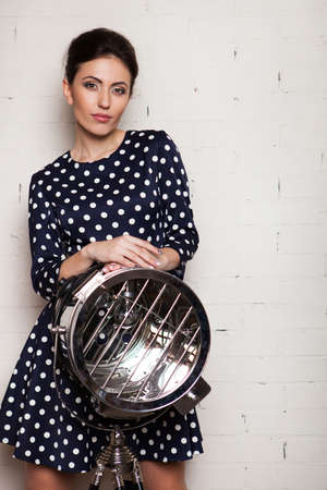 Portrait of a pretty woman with a beautiful smile in a dress in peas. Girl in minimalistic inteior againist a white brick wall. Fashion and beauty.の写真素材