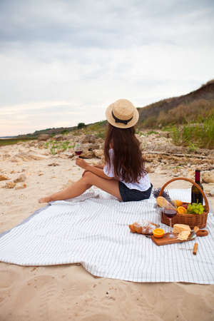 Young woman in Summer Picnic on the beach at sunset in the white plaid, food and drink conception.の写真素材