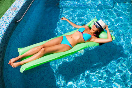Woman relaxing on mattress in the pool water in hot sunny day. Summer holiday idyllic. Pool party