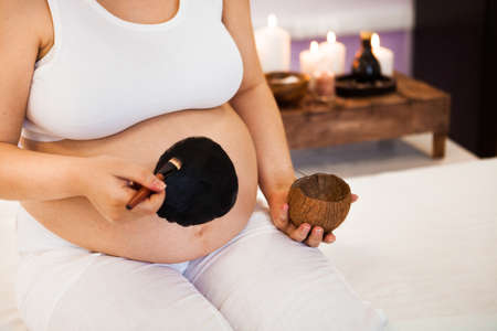 Young pregnant woman relaxing at Spa salon, Spa treatment black mask. Ð¡oncept of beauty and healthの写真素材