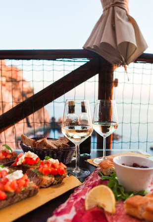 Romantic dinner for two at sunset. White wine and Tasty italian snack: fresh bruschettes  and meat...