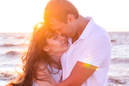 Happy young family relaxing on beach at sunset. Family traveling romantic concept
