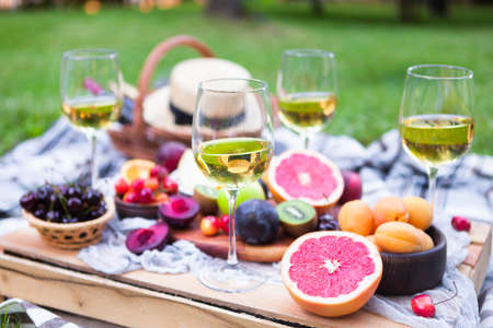 Picnic background with white wine and summer fruits on green grassの写真素材