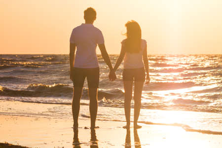 Happy young family relaxing on beach at sunset. Family traveling romantic conceptの写真素材