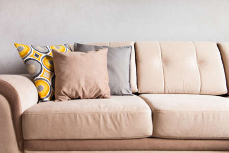 Multi-colored pillows on a beige fabric sofa, the concept of home comfort and cozy, copy space, close-upの写真素材