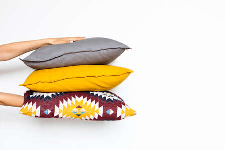 Colorful pillows in women's hands on a white isolated background, the concept of home comfortの写真素材