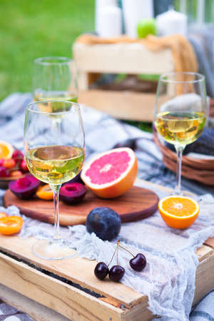 Picnic background with white wine and summer fruits on green grass
