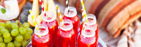 Picnic on the beach at sunset in the style of boho. Concept outdoors evening healthy meal with fruit and juice.の写真素材