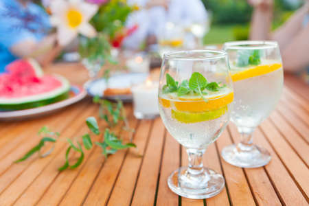 Two glasses of lemonade. Family outdoor dinner in  garden in summertime at sunset. Picnic food and...