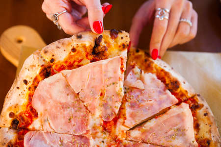 Italian food dinner. Woman eating Pizza with tomato prosciutto and mozzarella and drink  white wine summer outdoor restaurantの写真素材