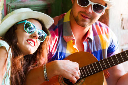 Happy smiling couple in sunglass and hat  with guitar drinking juice spending carefree time...