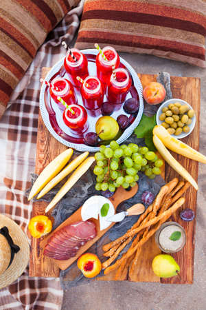 Picnic on the beach at sunset in the style of boho. Concept outdoors evening healthy meal with fruit and juice.の写真素材