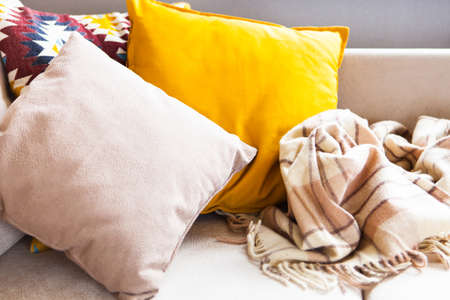 Cushions and plaid on the beige sofa close up with copy space. Sweet home and cozy concept. Indoorsの写真素材