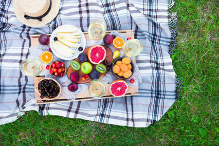 Picnic background with white wine and summer fruits on green grassの写真素材