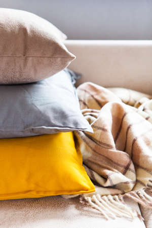 Cushions and plaid on the beige sofa close up with copy space. Sweet home and cozy concept. Indoorsの写真素材