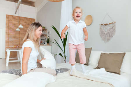 Mother and her daughter child girl playing and hugging in bedroom. Happy loving family.の写真素材